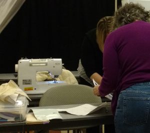 Volunteers review directions for creating garment protectors.