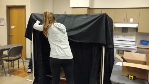 Volunteers hangs material for art easel.