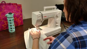 Volunteer sews a garment protector.