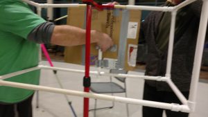 Volunteers construct an art easel from PVC pipe