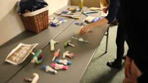 Volunteers examine a table of various tools with added grip support.